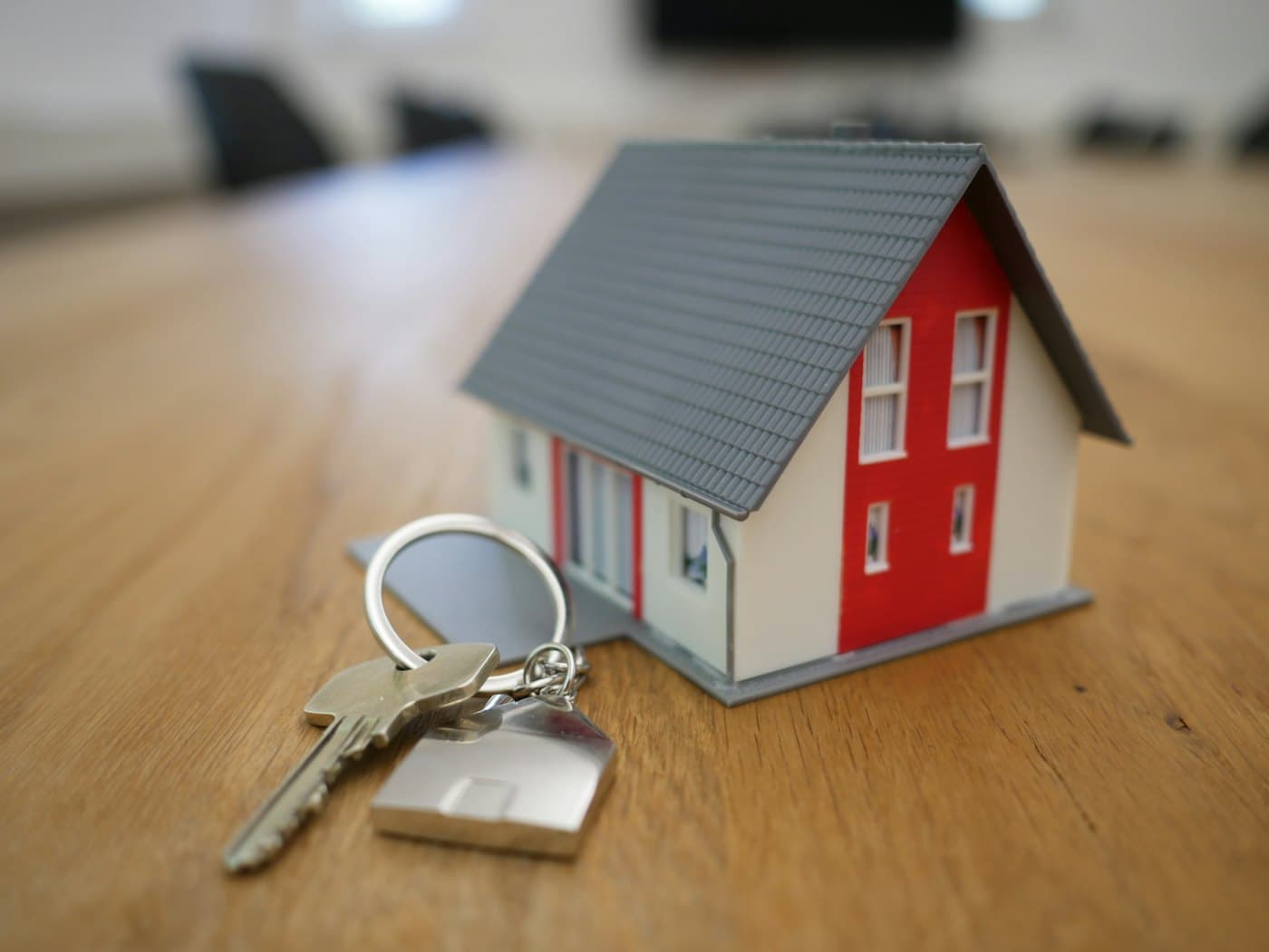 House keys with a model home on a wooden desk